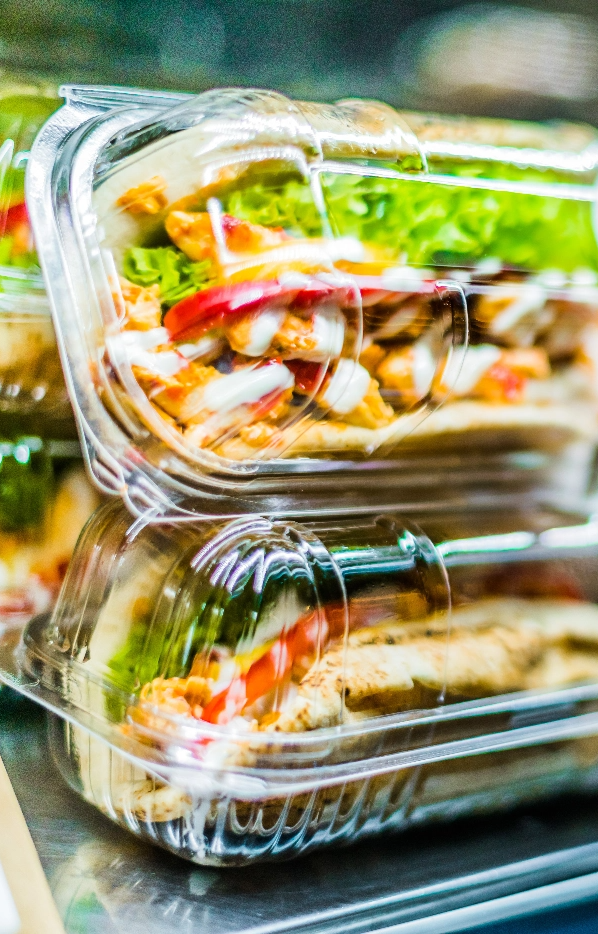 Fresh sandwiches in packaged individually in clamshell containers sit on a fridge shelf.